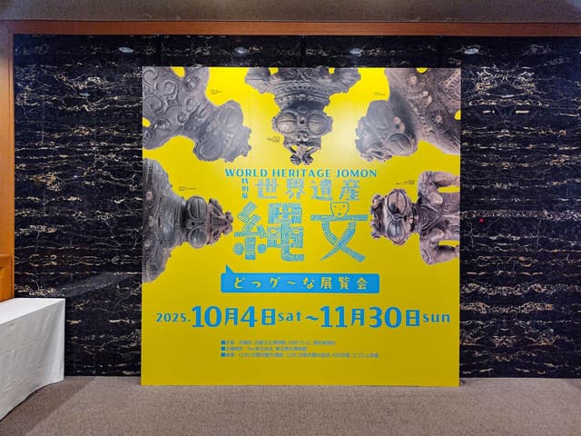 展覧会の入り口パネル。遮光器土偶に「どっグ~な展覧会」の吹き出しがあしらわれている