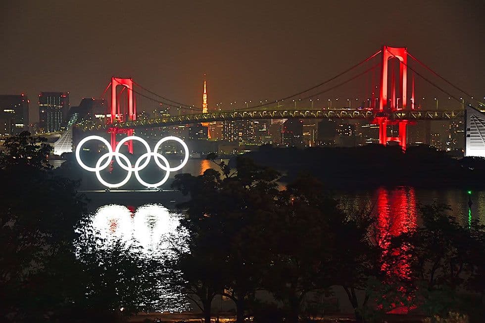 東京・お台場で夜間に点灯する五輪のモニュメント。新型コロナウイルス感染拡大への警戒を呼びかける「東京アラート」が出た2日、レインボーブリッジ(奥)が赤くライトアップされた=6月2日、恵原弘太郎撮影